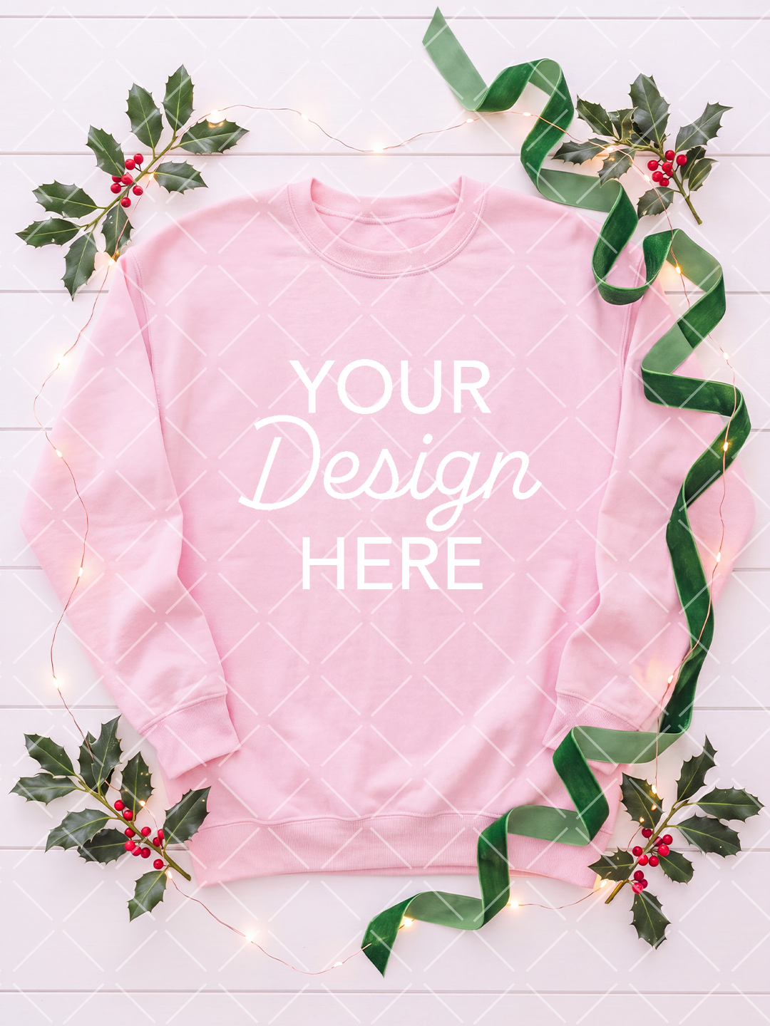 Pink crewneck sweatshirt Christmas mockup arranged with holly branches, red berries, green velvet ribbon, and glowing string lights on a pale wood background.
